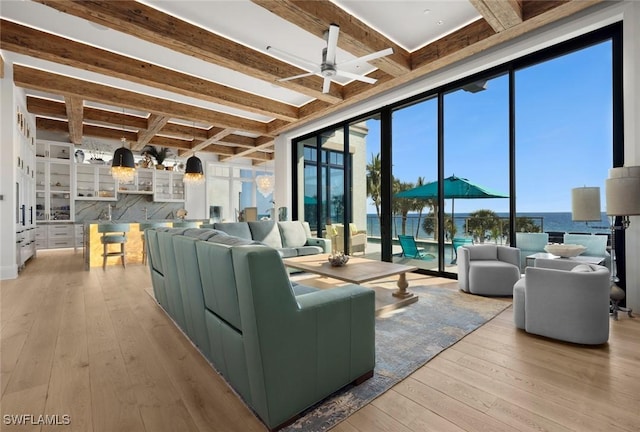 living room with a water view, ceiling fan, beam ceiling, and light hardwood / wood-style floors