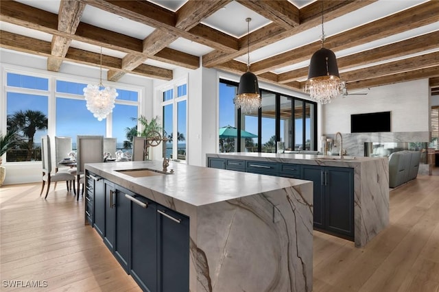 kitchen with an inviting chandelier, decorative light fixtures, and a center island with sink