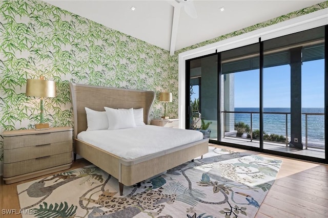 bedroom featuring hardwood / wood-style flooring, access to outside, ceiling fan, and a water view