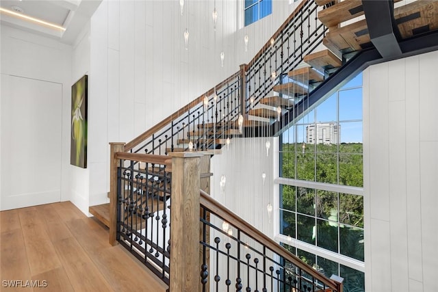 stairs with a towering ceiling and hardwood / wood-style floors