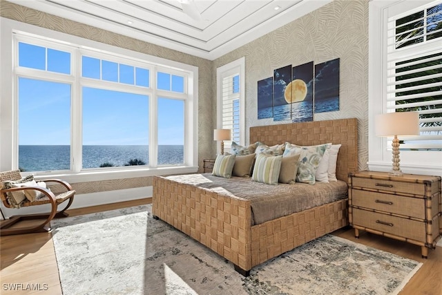 bedroom with a water view and light hardwood / wood-style flooring