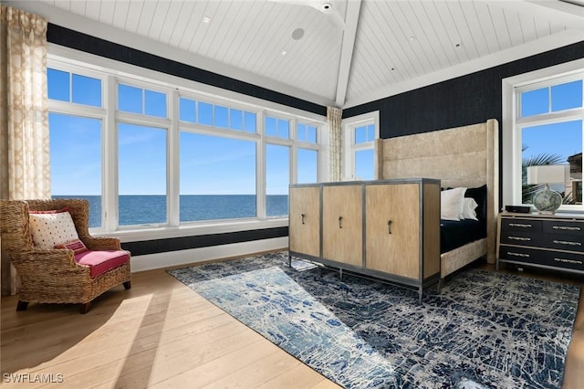 bedroom featuring a water view, lofted ceiling, and dark hardwood / wood-style floors