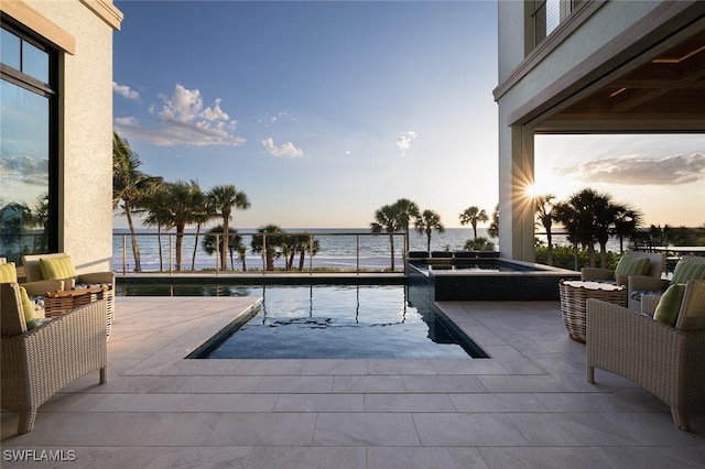 pool at dusk featuring a water view, outdoor lounge area, and a patio area