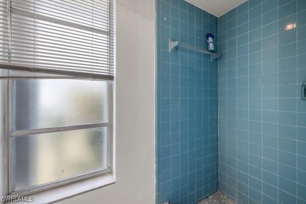 bathroom with a healthy amount of sunlight and tiled shower