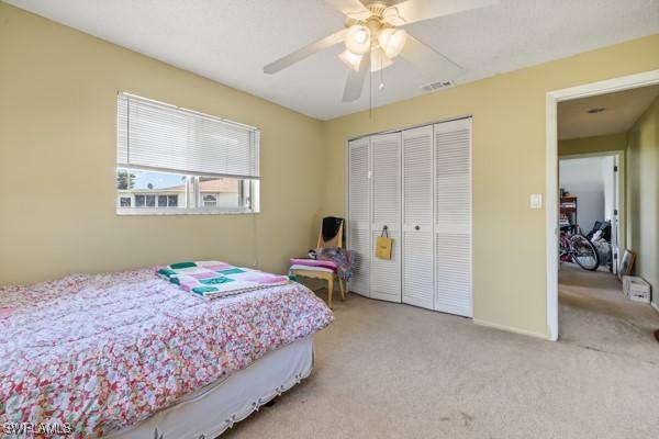 carpeted bedroom featuring a closet, visible vents, and ceiling fan