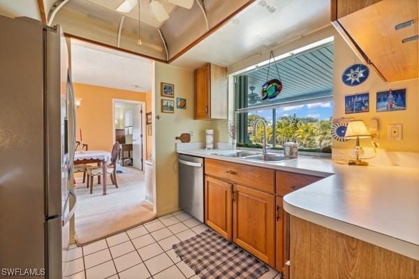 kitchen with brown cabinets, light countertops, appliances with stainless steel finishes, light tile patterned flooring, and a sink