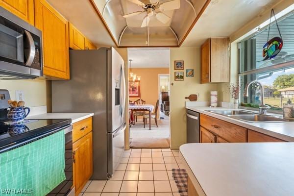 kitchen with sink, light tile patterned floors, ceiling fan with notable chandelier, and appliances with stainless steel finishes