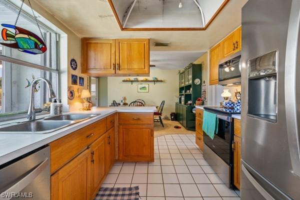 kitchen with stainless steel appliances, sink, light tile patterned floors, and kitchen peninsula