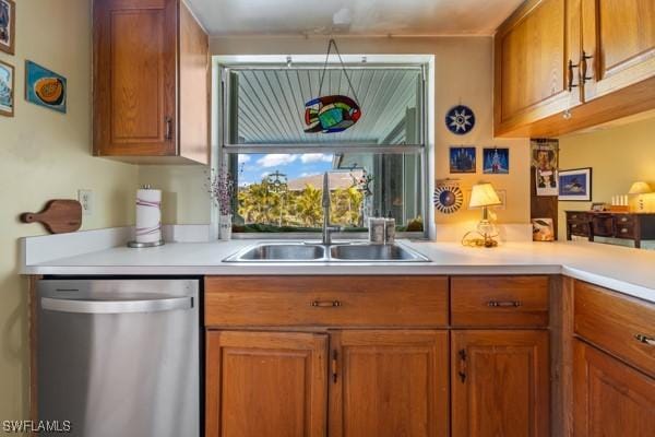 kitchen featuring light countertops, stainless steel dishwasher, brown cabinetry, and a sink