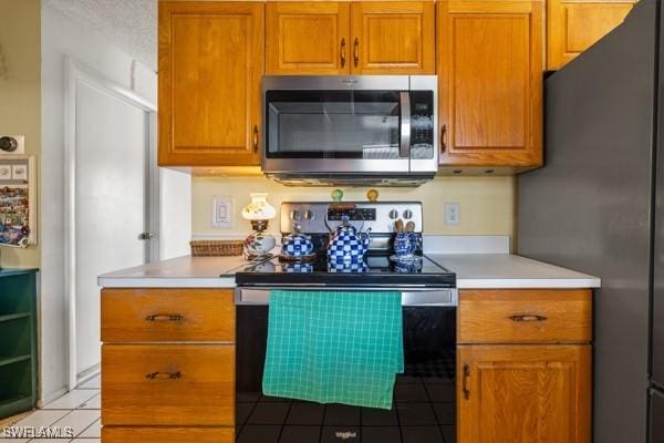 kitchen with appliances with stainless steel finishes, tile patterned flooring, and a textured ceiling