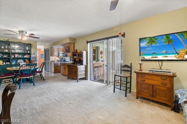 living room with a textured ceiling, light colored carpet, and ceiling fan