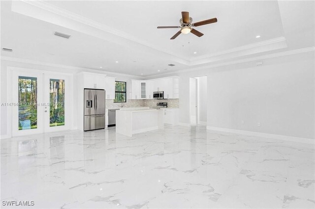 4091 56th Ave NE, Naples, FL 34120 - unfurnished living room with french doors, healthy amount of natural light, a tray ceiling, ceiling fan, and ornamental molding