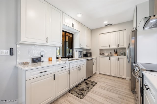 kitchen featuring tasteful backsplash, appliances with stainless steel finishes, sink, and white cabinets