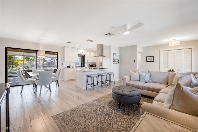 living room featuring light hardwood / wood-style flooring and ceiling fan