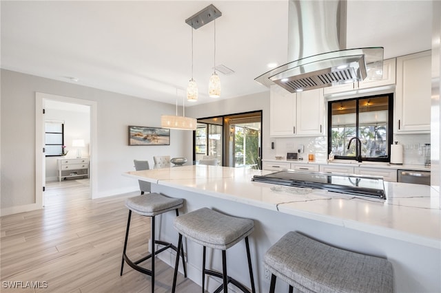 kitchen with island range hood, light stone countertops, and hanging light fixtures