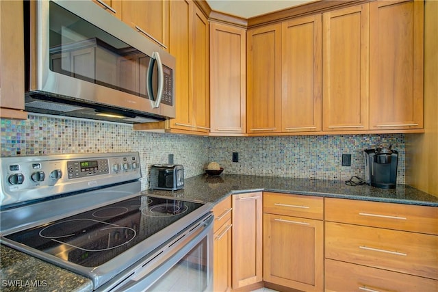 kitchen featuring backsplash, dark stone counters, and appliances with stainless steel finishes