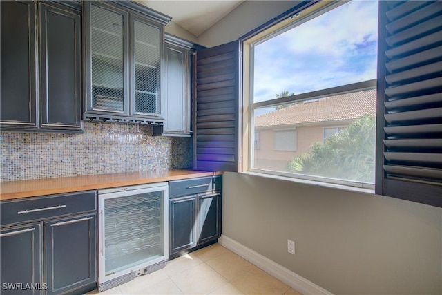 13911 Lake Mahogany Blvd Unit 2922, Fort Myers, FL 33907 - bar featuring wine cooler, light tile patterned flooring, baseboards, tasteful backsplash, and a dry bar