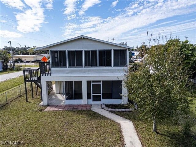 back of property with a yard and a sunroom