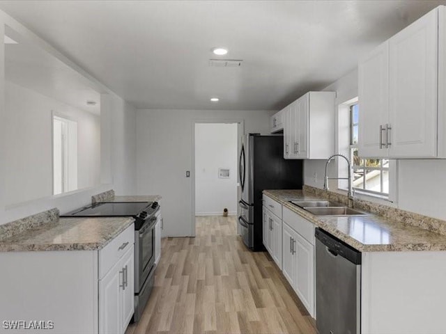 kitchen with appliances with stainless steel finishes, sink, light hardwood / wood-style flooring, and white cabinets