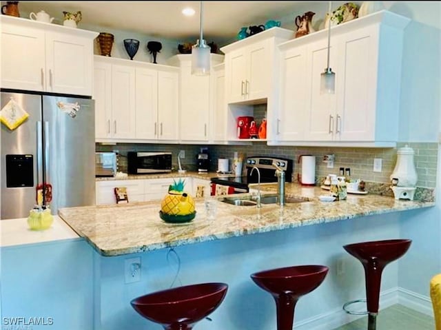 kitchen with sink, white cabinets, decorative backsplash, hanging light fixtures, and stainless steel appliances