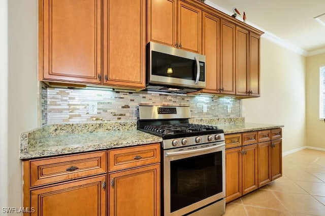 kitchen with crown molding, appliances with stainless steel finishes, tasteful backsplash, light stone countertops, and light tile patterned flooring