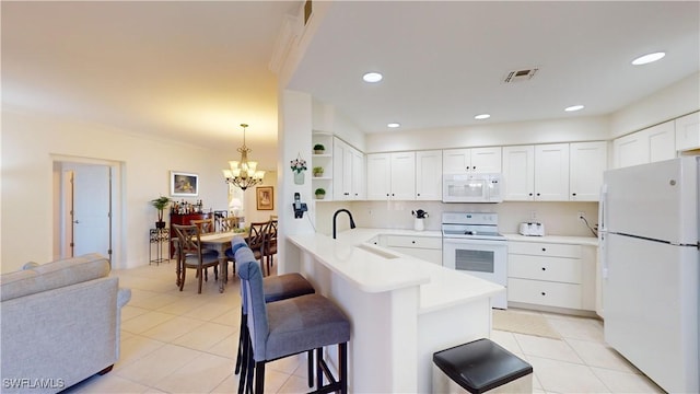 kitchen featuring white cabinetry, sink, a kitchen bar, kitchen peninsula, and white appliances