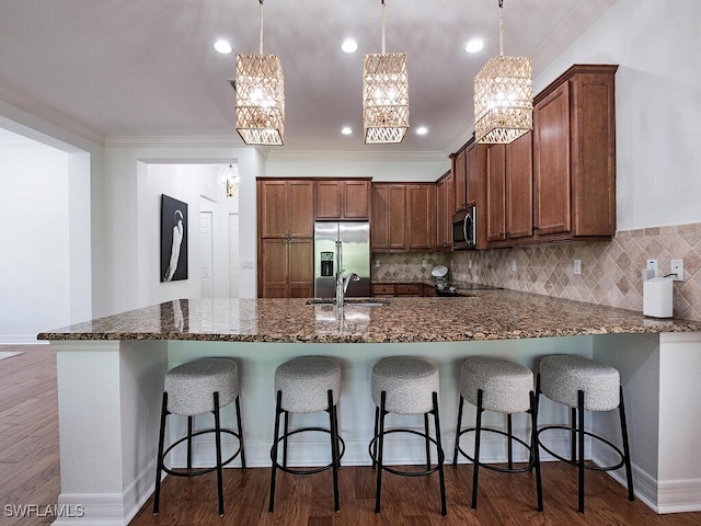 kitchen with appliances with stainless steel finishes, sink, decorative backsplash, and decorative light fixtures