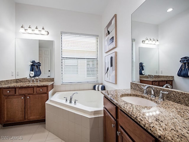 bathroom featuring tile patterned flooring, vanity, and tiled bath