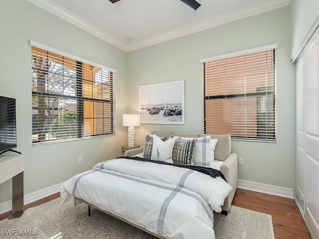 bedroom with wood-type flooring, ornamental molding, and a closet