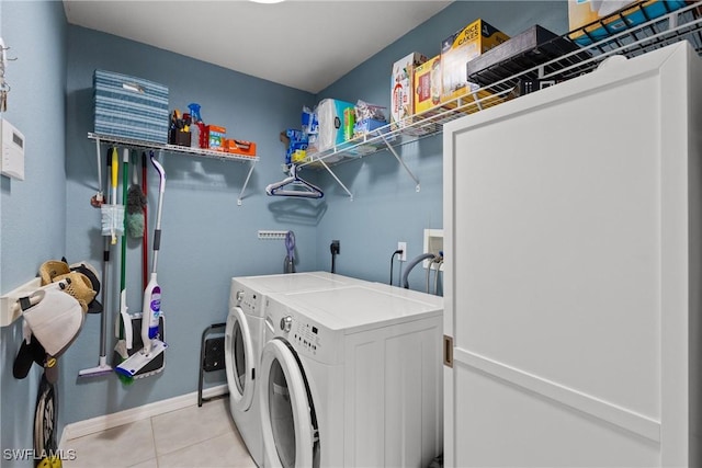 washroom with washer and dryer, laundry area, light tile patterned flooring, and baseboards