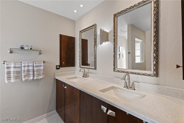 full bath featuring double vanity, a sink, and baseboards