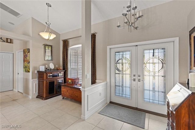 entryway with french doors, lofted ceiling, visible vents, light tile patterned flooring, and a chandelier