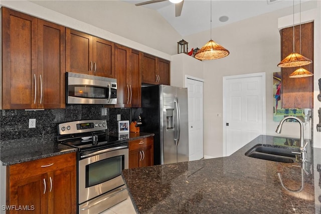 kitchen featuring pendant lighting, stainless steel appliances, a sink, and dark stone counters