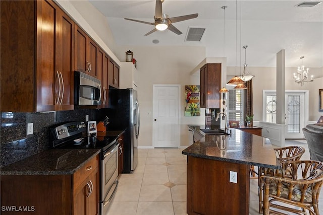 kitchen featuring hanging light fixtures, a kitchen bar, appliances with stainless steel finishes, and a sink