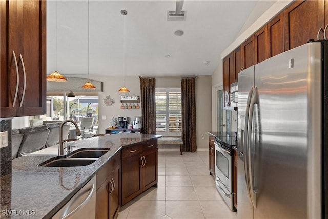 kitchen featuring stainless steel appliances, visible vents, hanging light fixtures, a sink, and dark stone counters