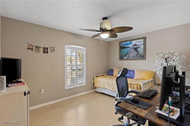 bedroom featuring a textured ceiling, light wood-type flooring, a ceiling fan, and baseboards