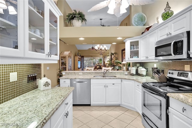 kitchen with appliances with stainless steel finishes, sink, white cabinets, decorative backsplash, and light tile patterned floors