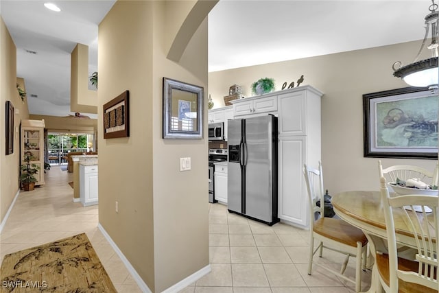 kitchen featuring stainless steel appliances, white cabinetry, light tile patterned floors, and ceiling fan