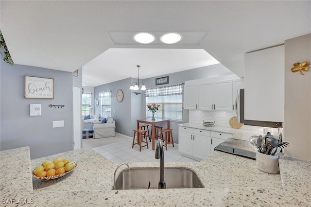 kitchen with decorative light fixtures, white cabinetry, sink, a chandelier, and decorative backsplash