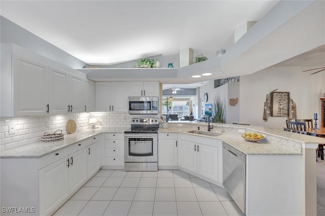 kitchen featuring light stone counters, appliances with stainless steel finishes, kitchen peninsula, decorative backsplash, and white cabinets