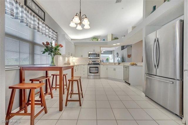 kitchen with vaulted ceiling, pendant lighting, white cabinetry, decorative backsplash, and stainless steel appliances