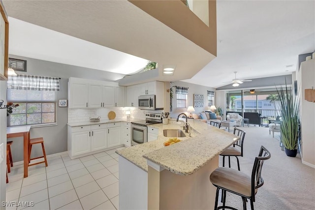 kitchen featuring sink, appliances with stainless steel finishes, a kitchen breakfast bar, kitchen peninsula, and white cabinets