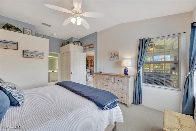 bedroom featuring light carpet, ensuite bath, vaulted ceiling, and ceiling fan