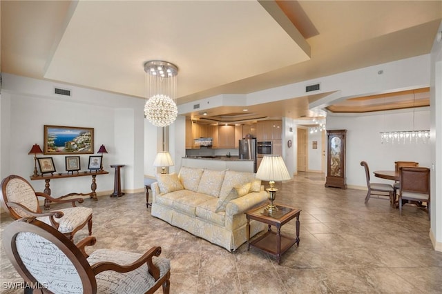 living area with a raised ceiling, visible vents, baseboards, and an inviting chandelier