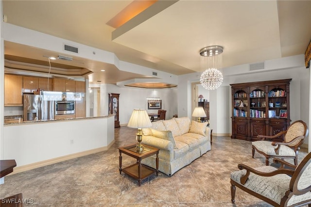 living area with baseboards, visible vents, and a tray ceiling