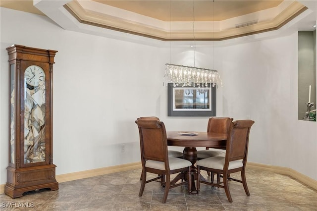 dining area with a raised ceiling, ornamental molding, and a chandelier