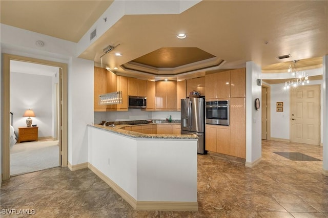 kitchen featuring a tray ceiling, kitchen peninsula, stone counters, pendant lighting, and stainless steel appliances