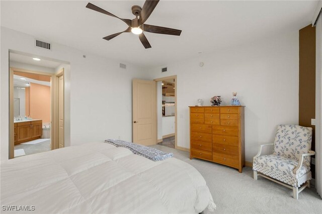 bedroom featuring light colored carpet, ceiling fan, and ensuite bathroom