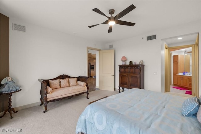 bedroom with ceiling fan, ensuite bath, and light carpet