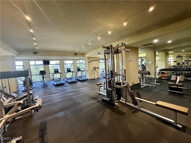 exercise room featuring rail lighting, visible vents, and vaulted ceiling